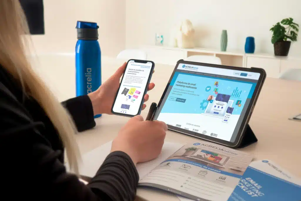 Photo of a woman sitting at a table using a tablet and holding a smartphone
