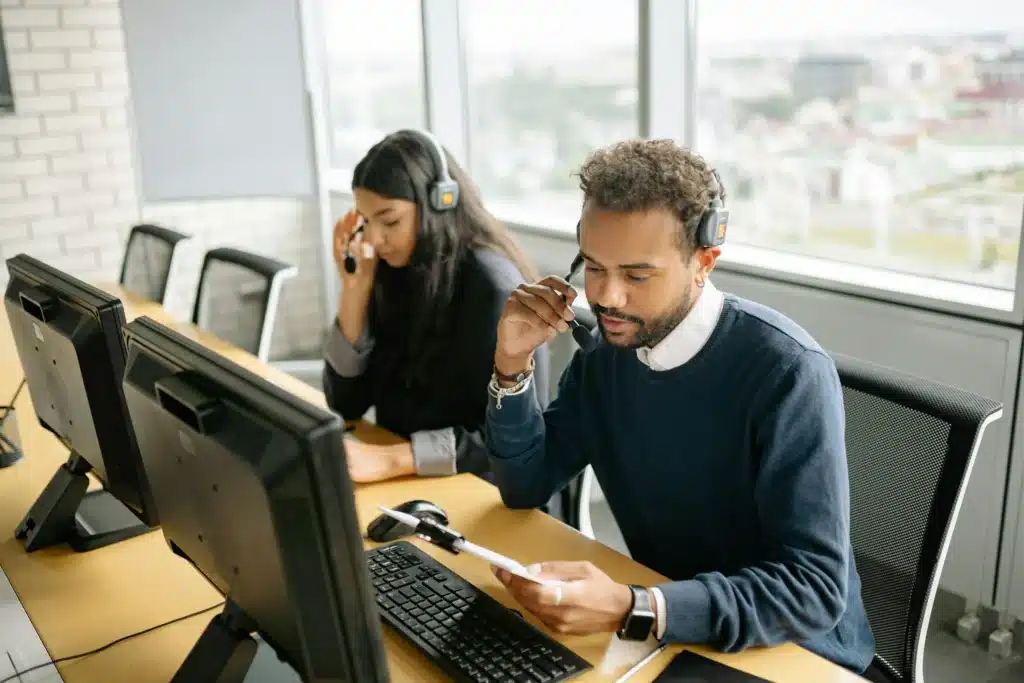 A photo of an IT support team at work in an office, wearing headsets and providing computer support services to clients.