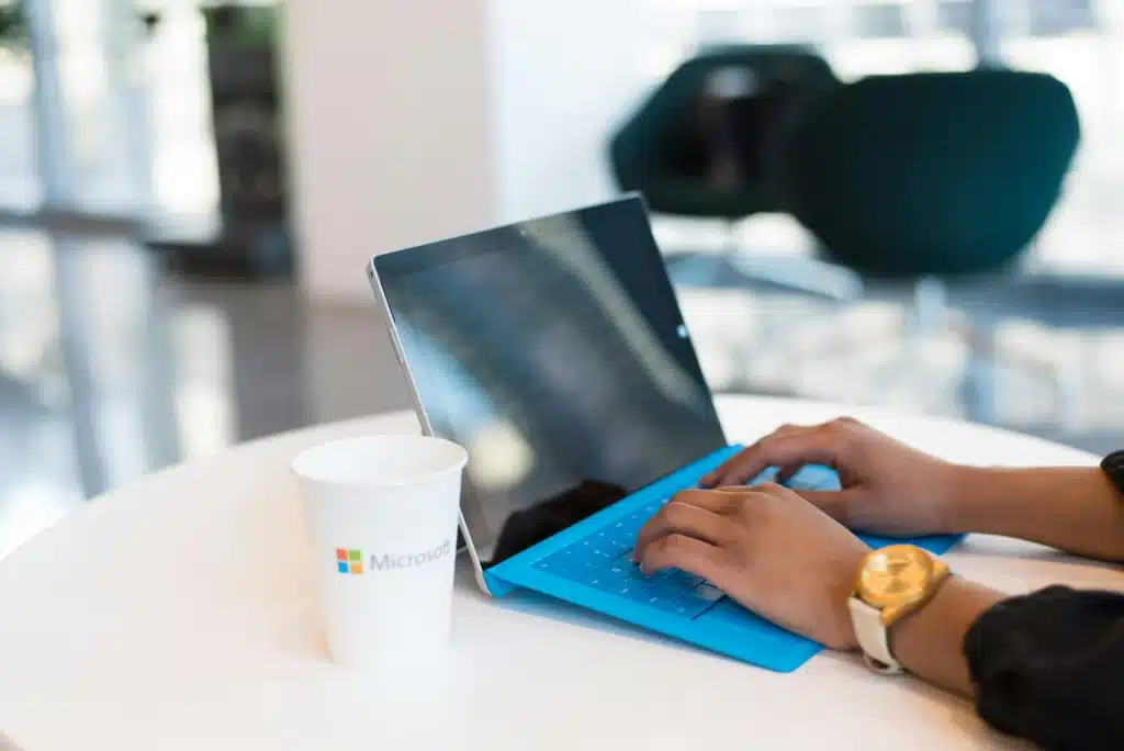 Photo of a blue Microsoft Surface and a cup with the Microsoft logo for Outlook QR code