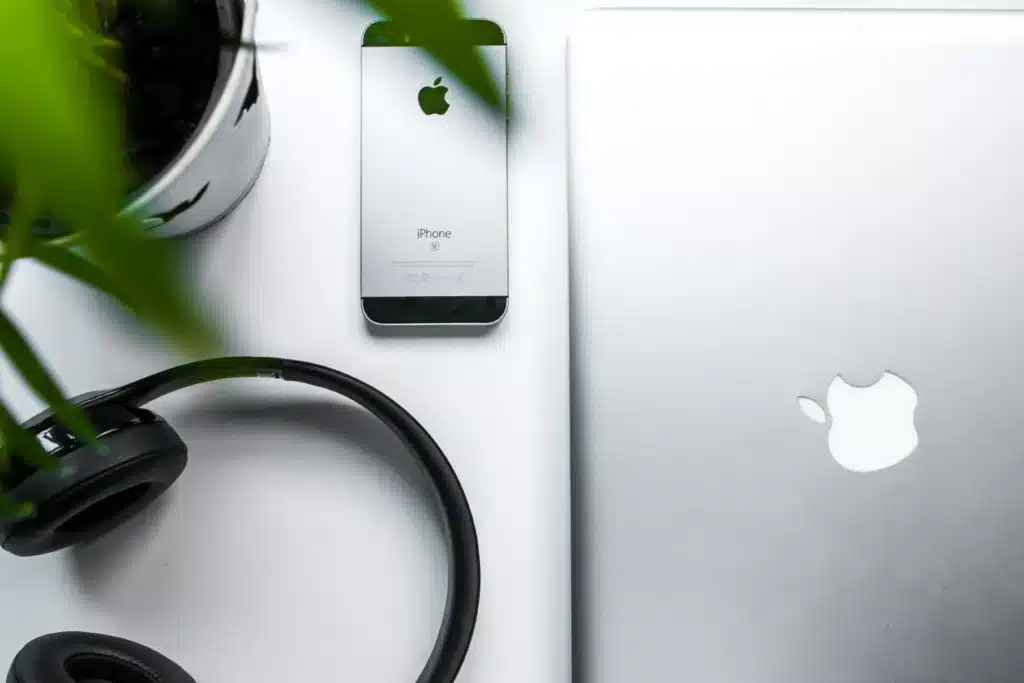 Black headphones and silver iPhone next to silver Macbook