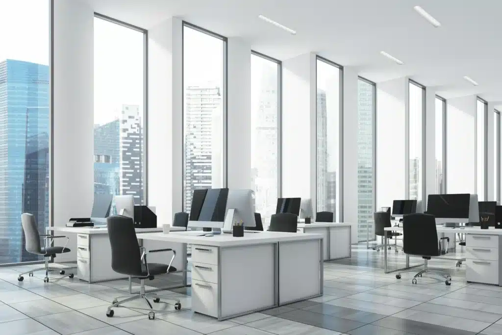 Open office space with several desks and iMacs next to view of tall buildings