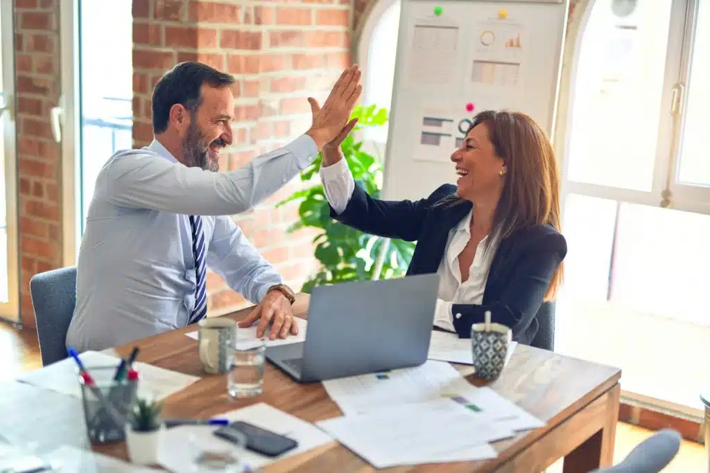Photo of two employees smiling and high-fiving while working on a network operating system
