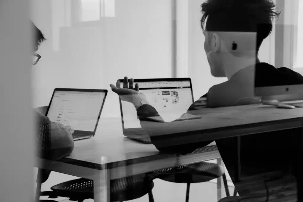 Men at table on MacBooks