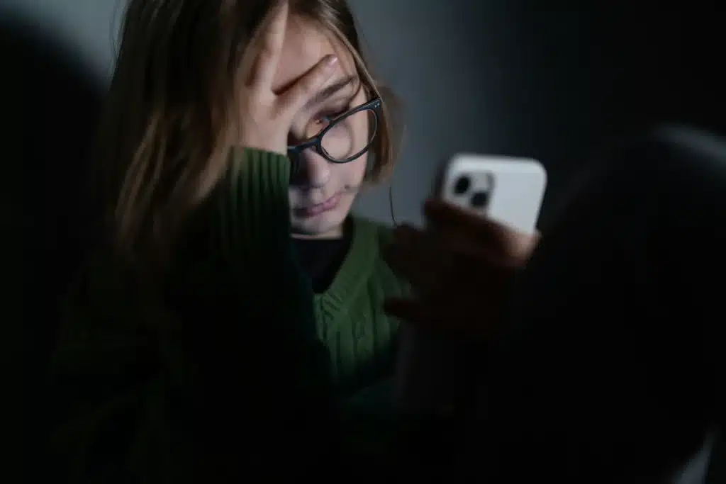 Girl looking at her white iPhone with a frustrated expression