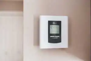 a thermostat in front of a beige wall.
