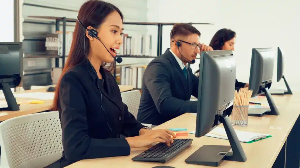 Help desk support team of three people wearing business attire while working on desktop computers
