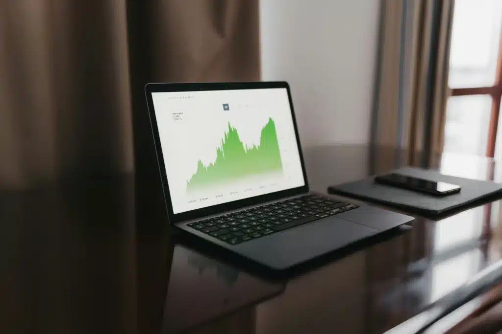 Macbook open on table with green chart on screen
