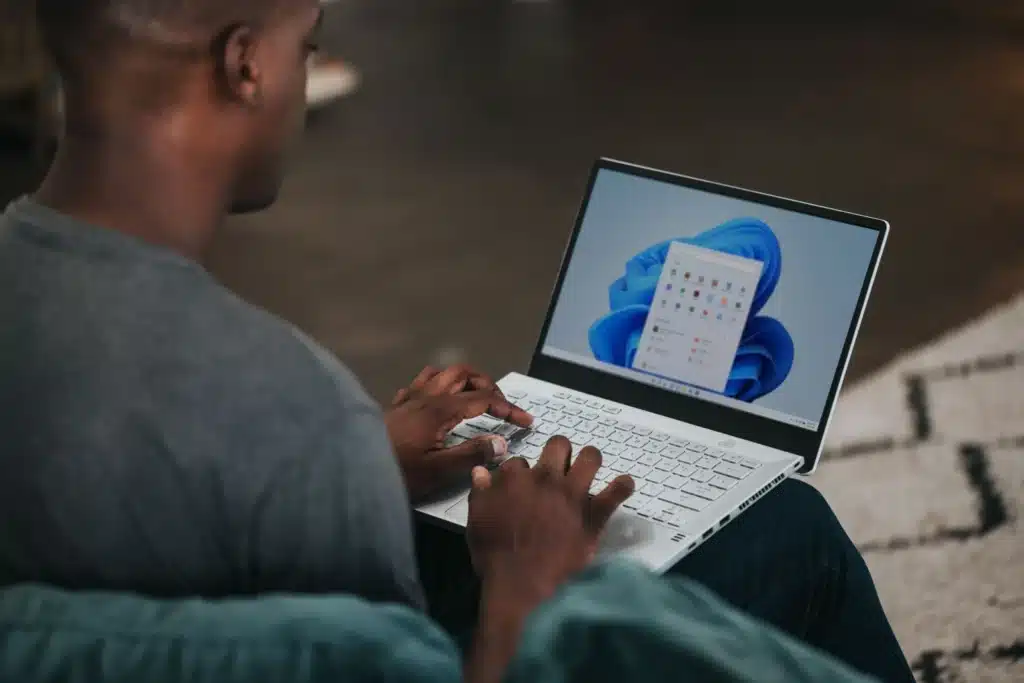 Man typing on a laptop resting on his lap.