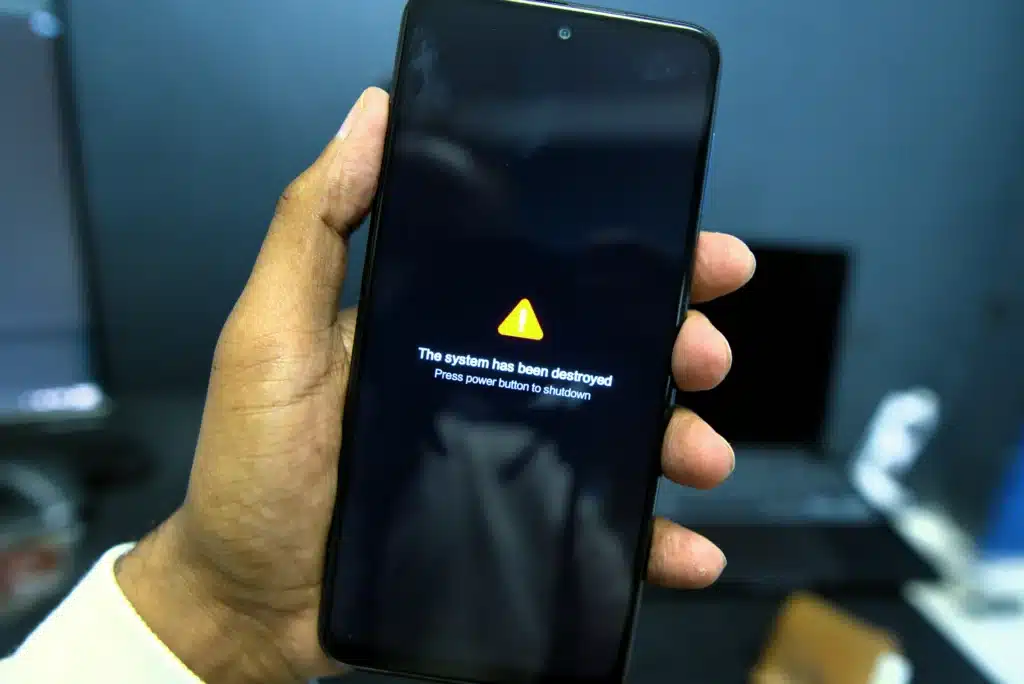 Photo of a man's hand holding a smartphone with a caution error on the screen