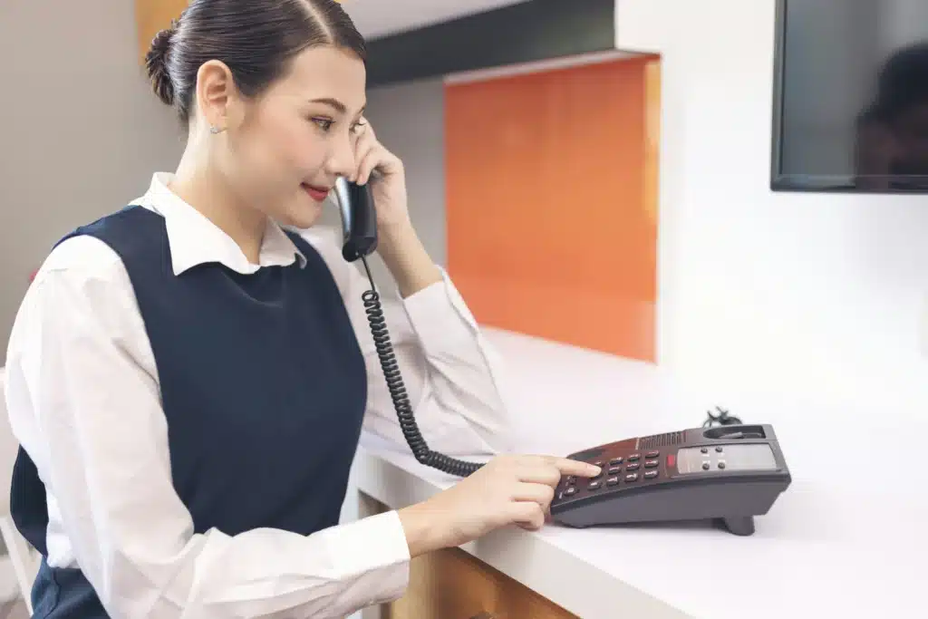 Woman smiling while calling on traditional landline in office