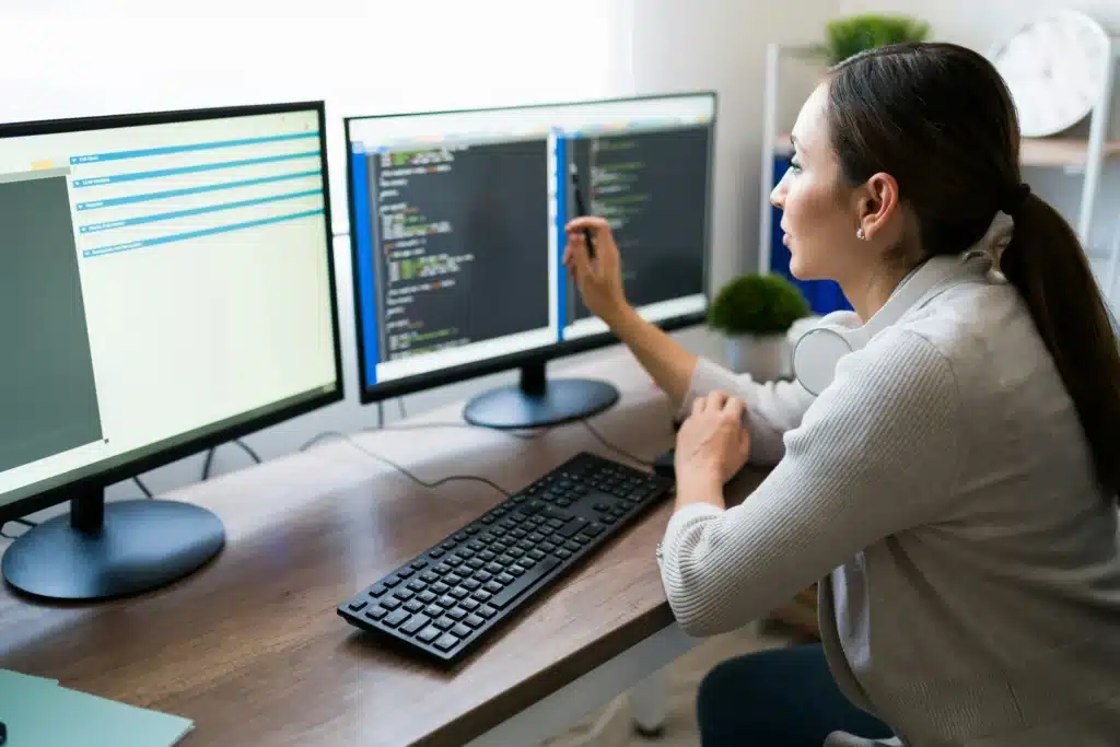 Woman working at home on dual monitors at a desk