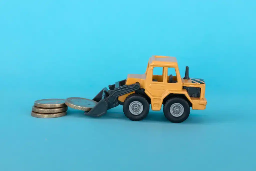 Yellow bulldozer toy picking up silver coins on blue backdrop