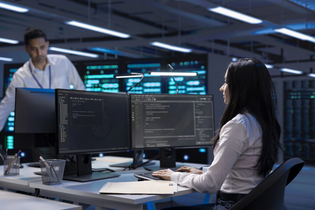 IT professionals monitoring systems and cybersecurity activity in a modern server room while managing managed IT support services for business operations.