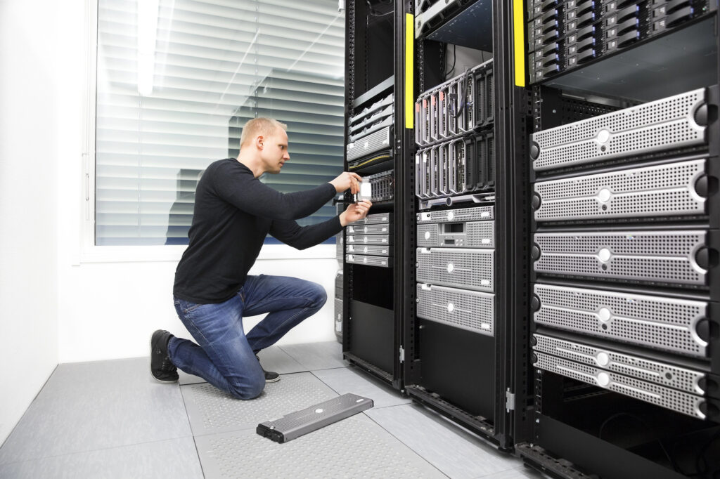 IT technician working in a server room preparing infrastructure for a secure cloud migration project for a growing business.